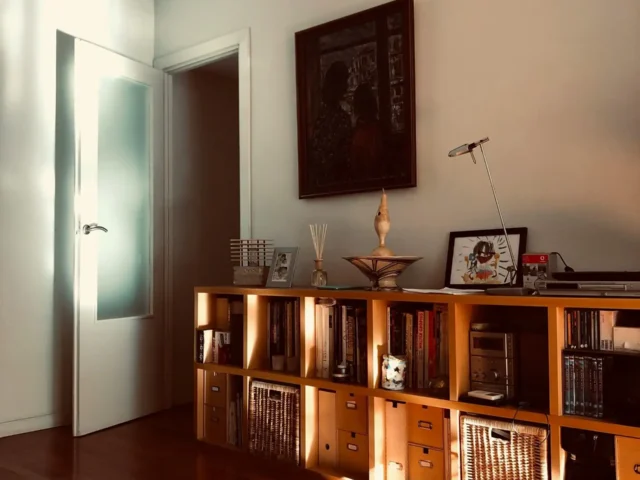 Rénovation intérieure : salon lumineux avec parquet verni, porte blanche vitrée et meuble bas en bois – travaux BTP.