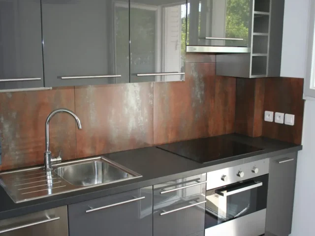 Rénovation de cuisine moderne : meubles laqués gris, plan de travail sombre, évier inox et crédence effet métal.